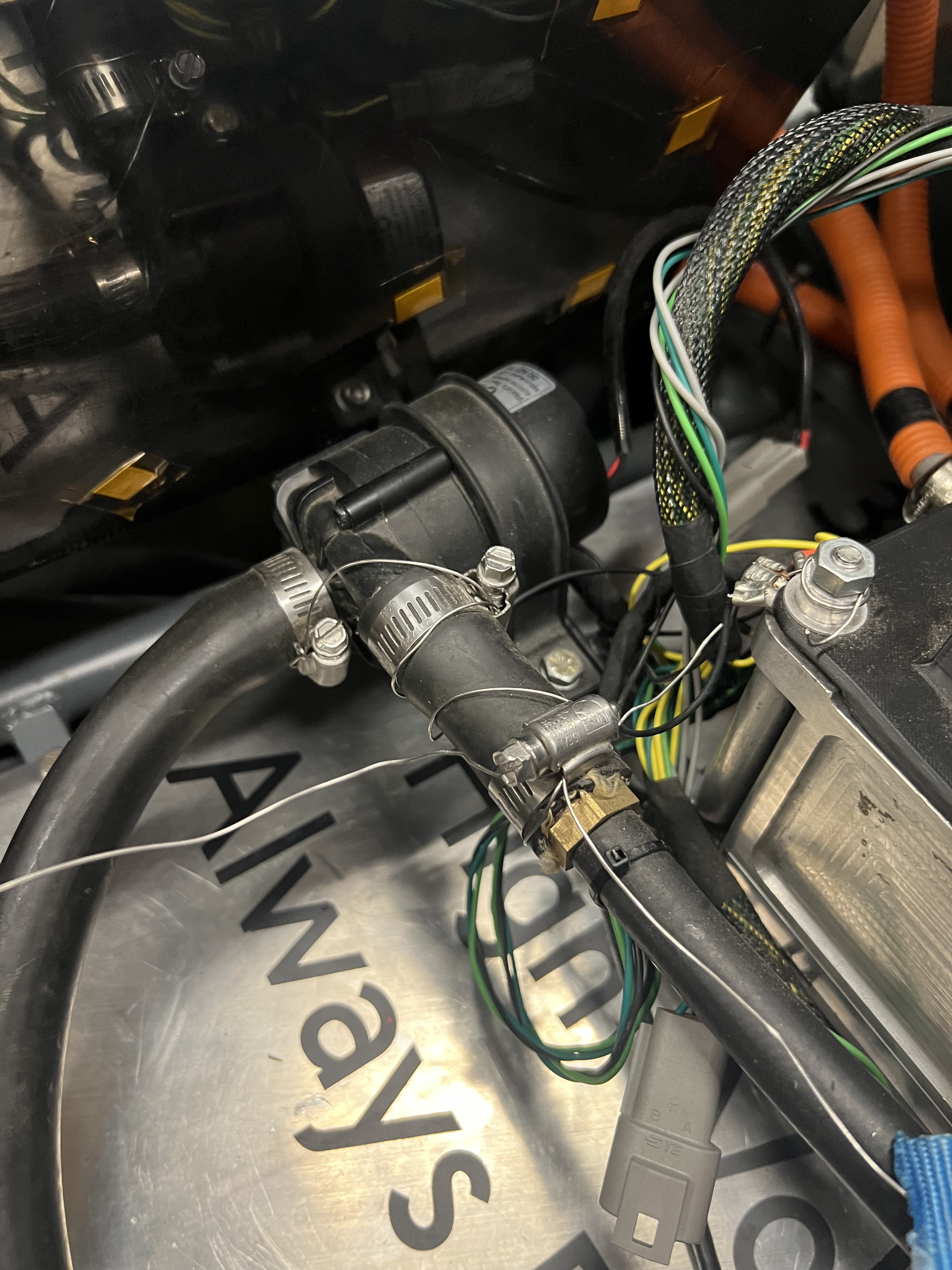 The coolant pump plumbed inline in the black coolant hose, with worm-drive clamps safety-wired in place