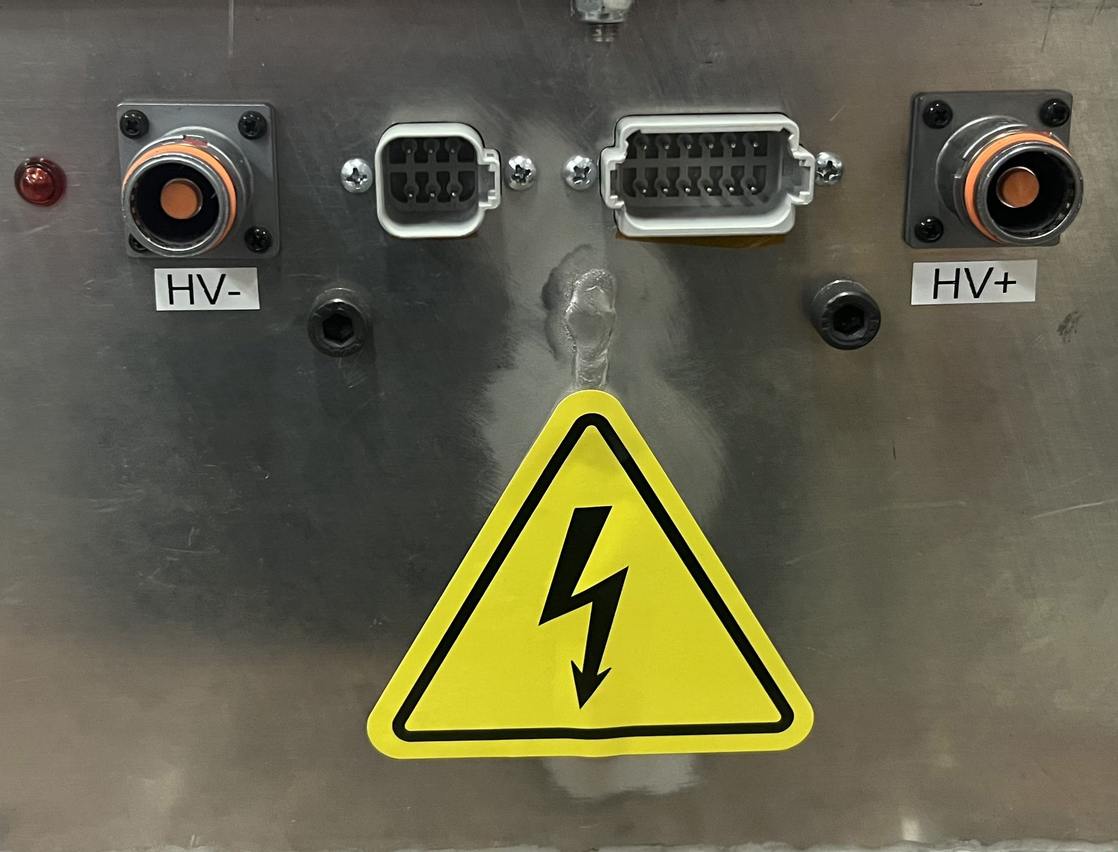 HV+ and HV- high-voltage connectors on the accumulator, with a high-voltage warning label