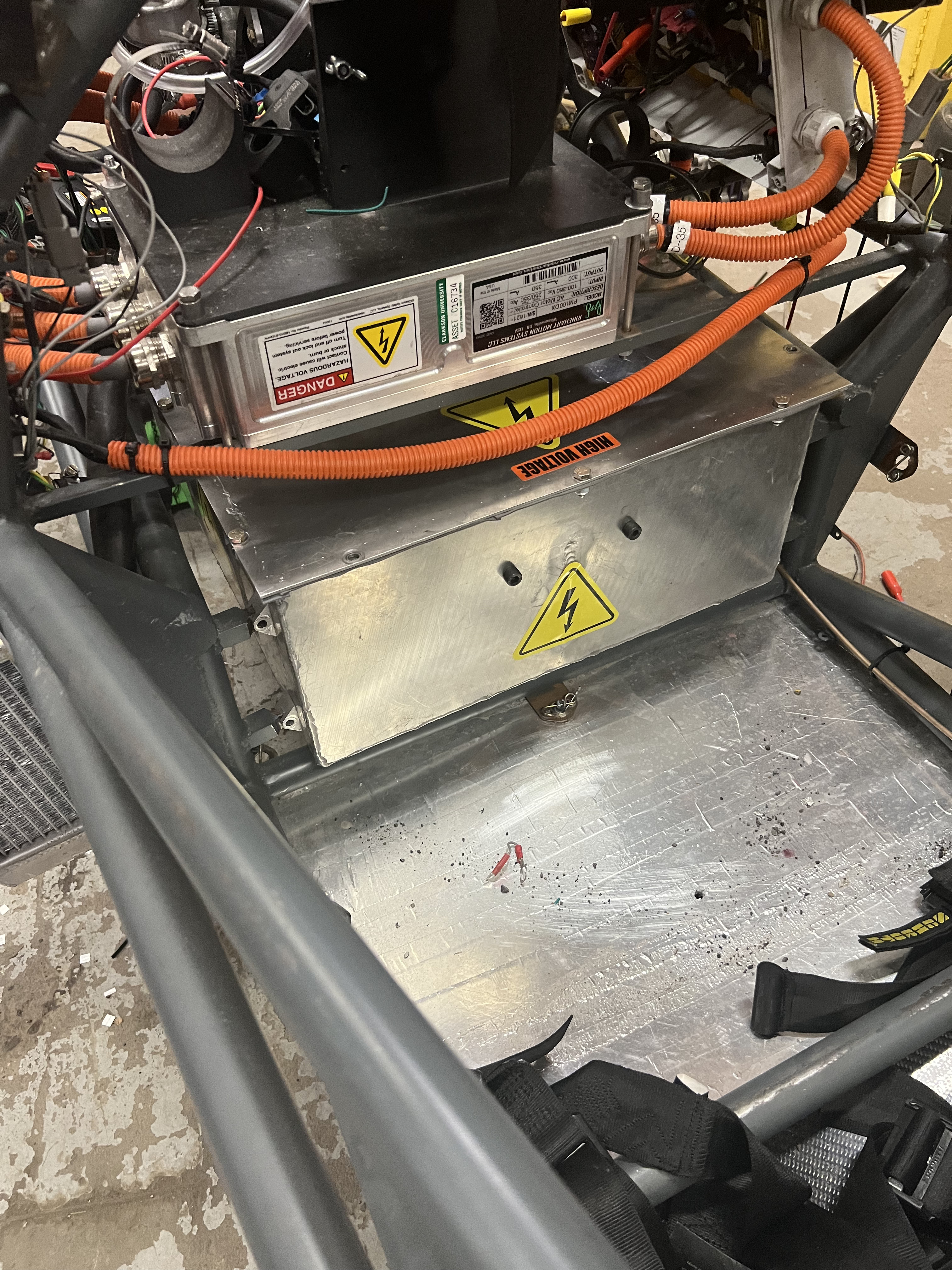 Cascadia Motion PM100DX motor controller mounted in the chassis, with orange high-voltage cabling and hazard warning labels