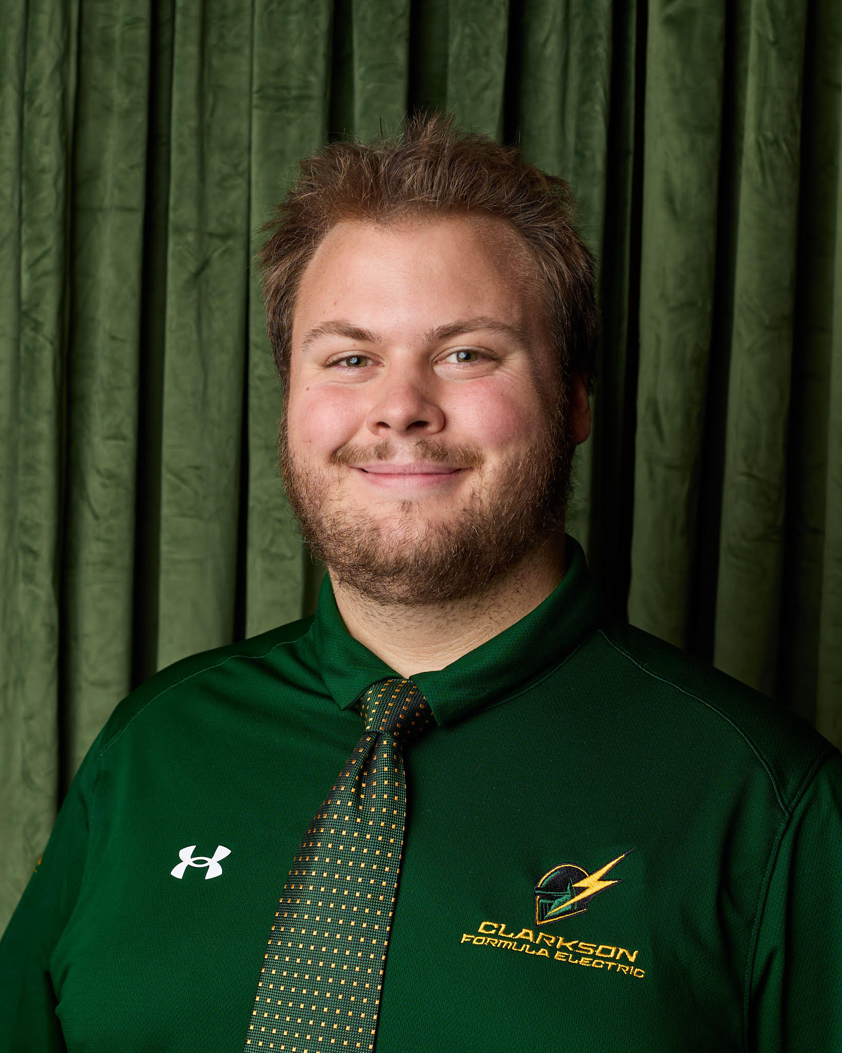 Matt Whispell in a green Clarkson Formula Electric polo and tie, against a green backdrop